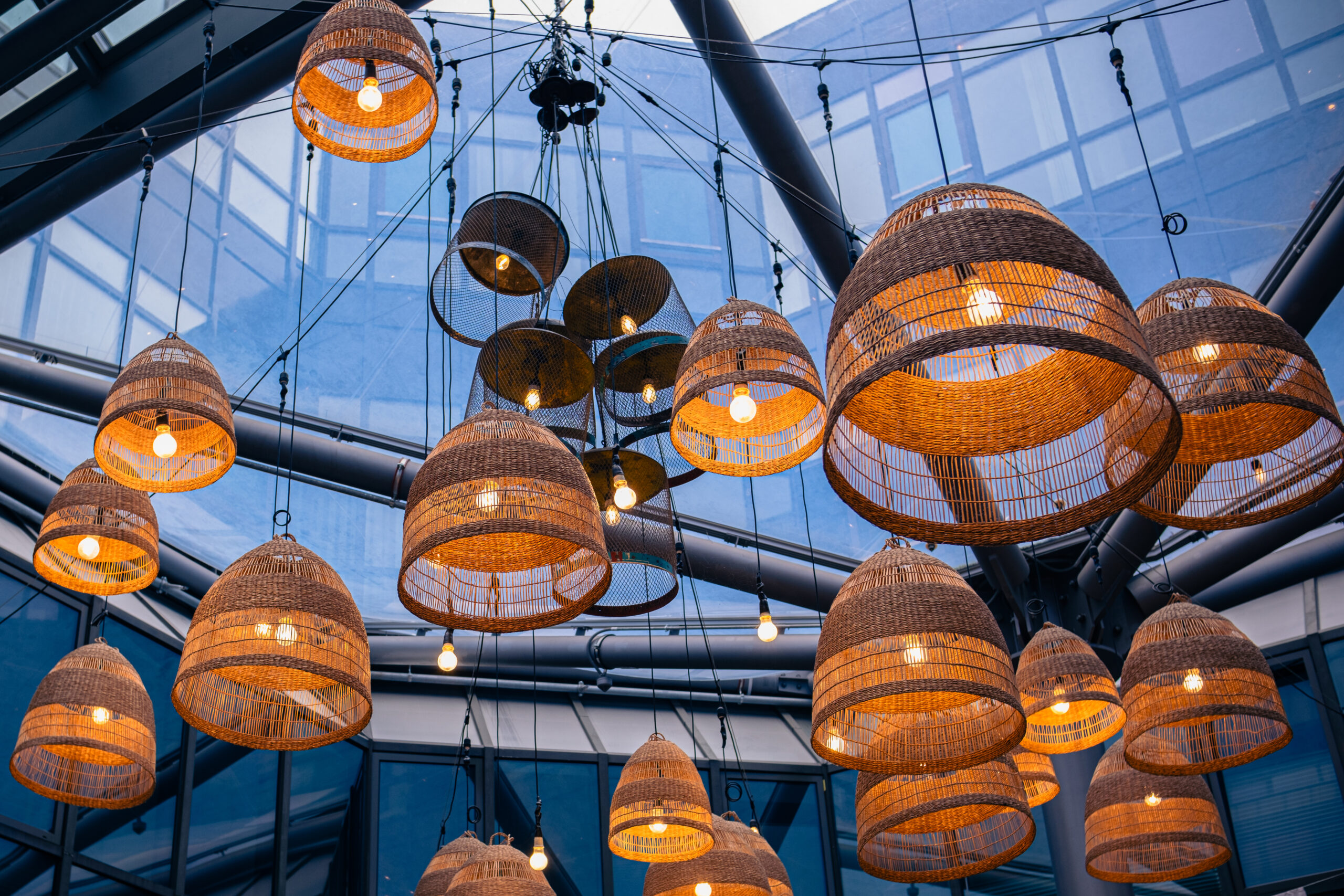 Lamps with wicker shades under a glass ceiling in modern business centre or restaurant.